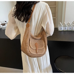 Detail of straw shoulder bag featuring a crescent shape and leather buckle pocket
