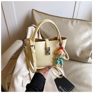 Detail of pale yellow bucket bag with pearl chain and cartoon girl charm accessory