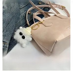 Detail of pink bucket bag with a cute monster fur ball charm and long shoulder strap
