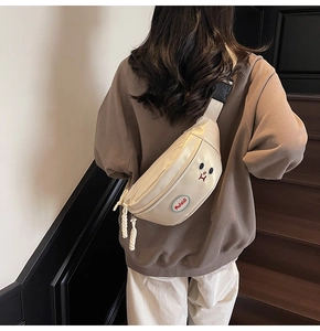 Dettaglio borsa a tracolla beige con design a orsetto e cordoncini intrecciati sulla zip