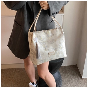 Detail of embroidery butterfly bucket bag with grey tassel and gold metal hardware