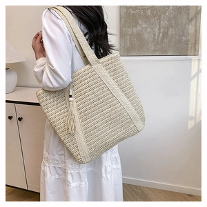 Detail of straw tote bag showing tight weave texture and black-white bead tassel