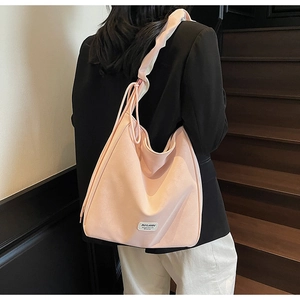Detail of light pink tote bag featuring wide pleated strap and side drawstring accents