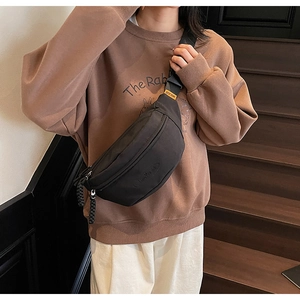 Detail of a black canvas chest bag with adjustable strap and dual zipper closure