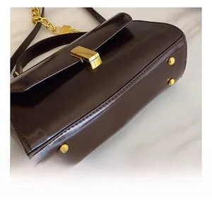 Close-up of golden protective studs on the bottom of this coffee brown leather handbag