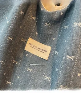 Close-up detail of blue denim tote bag with white bow embroidery and textile label