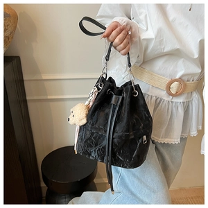 Detail of black drawstring bucket bag with pleated texture and cute teddy bear charm