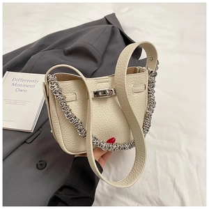 Dettaglio della chiusura a scatto in metallo argento su borsa in pelle litchi bianco crema