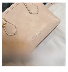 Detail shot of apricot leather bucket bag showing stitching and logo embossing