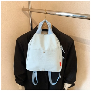 Detail view of light blue canvas multi-purpose bag hanging on a suit with a button pocket