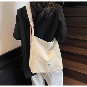 Minimalist beige hobo bag with MULAIDI label shown on a model against wooden stairs