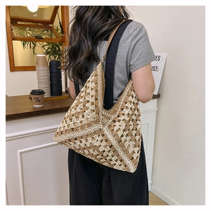 Close-up of a hollow-out crochet shoulder bag with brown leather straps on a model