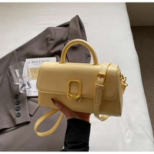 Vue détaillée du sac à main crème avec fermoir doré et texture en cuir lisse