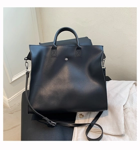 Detail view of large matte black tote bag with silver stud and adjustable shoulder strap