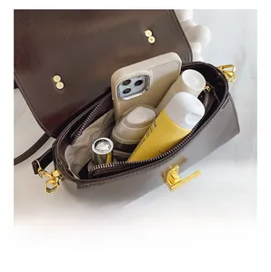 Macro view of dark brown leather square bag showing spacious interior with dual zip pockets