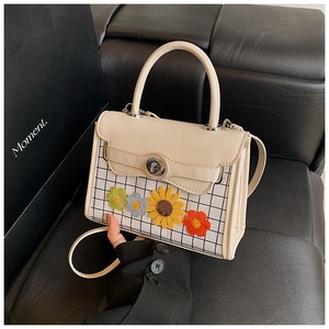 Détail du sac à carreaux beige avec fleurs en 3D et fermoir rotatif en métal poli