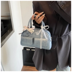 Detail of light blue Boston bag with ribbon and lace accents on front pockets