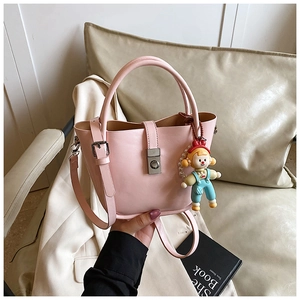 Detail of light pink leather bucket bag with silver twist lock and cute cartoon doll charm
