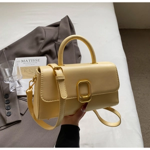 Détail d'un sac à main jaune en cuir avec boucle dorée et bandoulière amovible