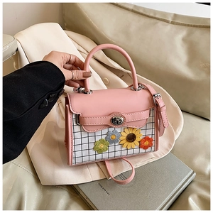 Gros plan du sac à main rose à carreaux avec broderie florale sur canapé beige