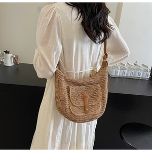 Detail of hand-woven straw shoulder bag with brown leather buckle and saddle shape design