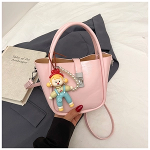 Pink bucket bag with pearl doll charm and detachable shoulder strap in detail view