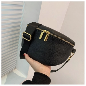 Detail shot of black pebble grain leather texture with gold metal zippers and nylon strap