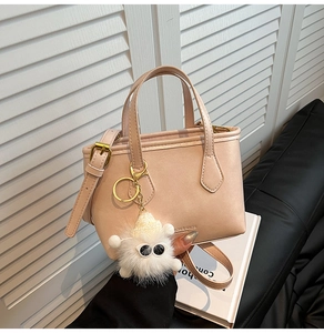 Detail of light pink bucket bag with plush monster charm and adjustable strap