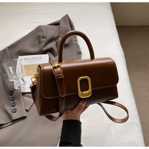 Détail d'un sac à main vintage en cuir marron avec boucle dorée et bandoulière réglable