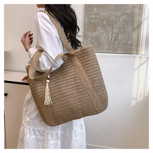 Detail of straw tote bag showing natural wood texture and decorative tassel with wooden beads