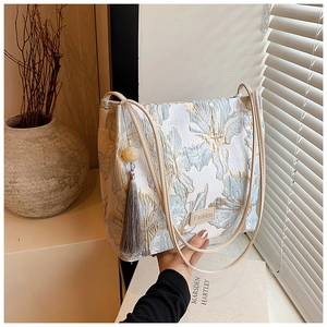 Detail of blue brocade bucket bag with golden floral patterns and silk tassel accessory