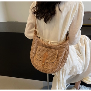 Close-up of straw beach bag with brown leather buckle and retro metal button detail