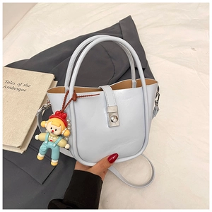 Detail of light blue bucket bag with silver clasp, pearl charm and cartoon pendant
