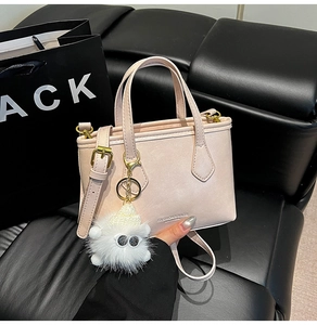 Close-up of pink PU bucket bag with plush charm and adjustable shoulder strap detail