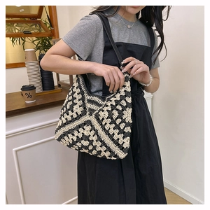 Detail of woven tote bag with black and white geometric patterns and leather strap
