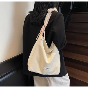 Detail of cream shoulder tote bag showing drawstring pleated strap and pink lining