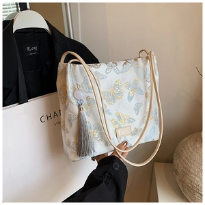 Detail of butterfly embroidery and silk tassel on a white satin bucket bag for Hanfu
