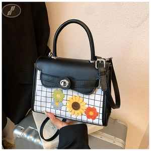 Détail du sac en cuir à carreaux avec broderie de tournesols et fermoir tournant argenté