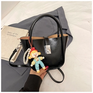 Detail of black patent leather bucket bag with silver twist lock and pearl doll charm