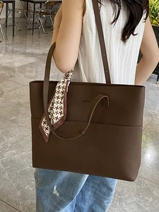 Large dark brown leather tote bag with silk scarf accessory for casual commuting