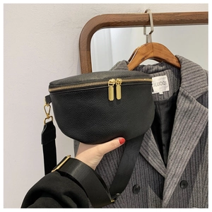Detail of black pebbled leather crossbody bag with gold zippers and wide fabric strap
