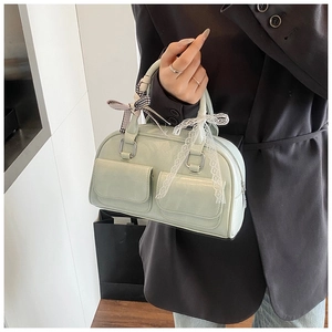 Detail of mint green Boston bag with pockets, plaid bow, and white lace ribbons
