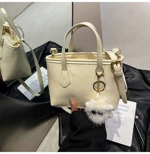 Détail du sac seau blanc cassé avec texture en similicuir et breloque en peluche