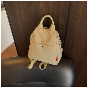 Detail of beige nylon multi-functional backpack with top handles and front magnetic pocket