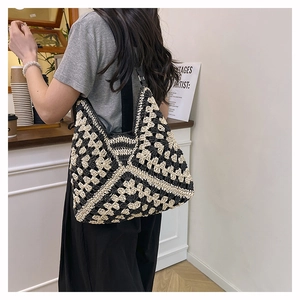 Detail view of a handmade crochet tote bag with black and white checkered flower patterns