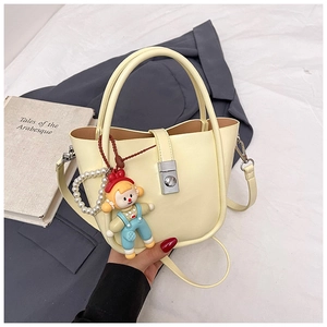 Detail of cream white bucket bag with metallic twist lock and pearl handle accessory
