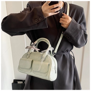 Detail view of a light green multi-pocket bowling bag with lace and bow accents