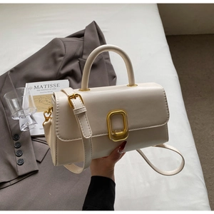 Détail d'un sac à main beige en cuir avec fermoir carré doré et poignée élégante