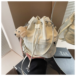 Detail of white marble print drawstring bucket bag with a cute plush dog pendant charm