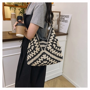 Detailed view of handmade black and white geometric crochet tote bag on a model